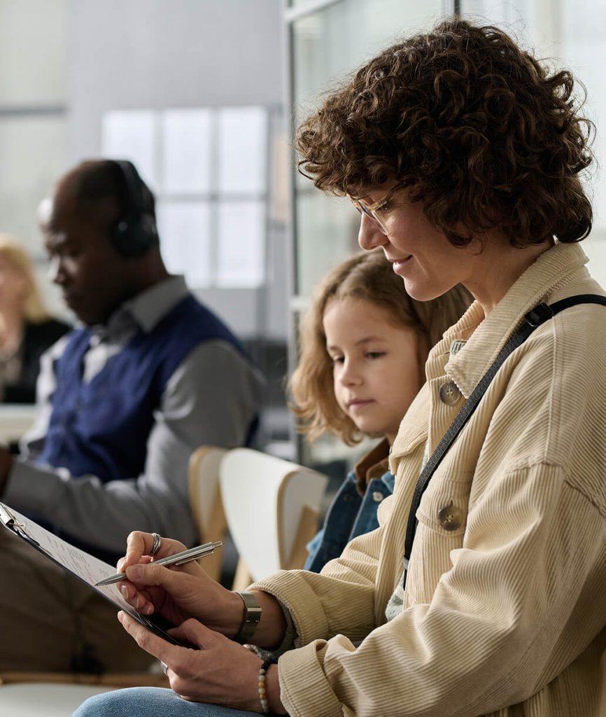 Woman fills out a form with child by her side